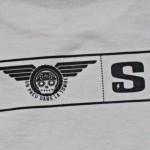 Gros plan sur la signature "Susokary" d'un t-shirt "Un pneu dans la tombe".